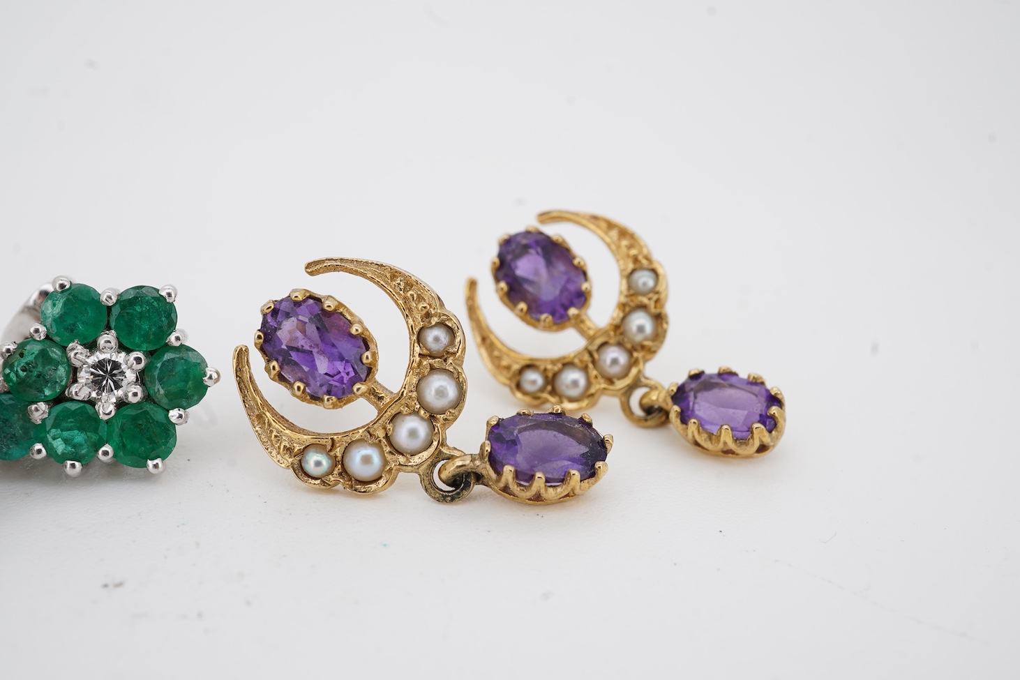A pair of mid to late 20th century white metal, emerald and diamond cluster set drop earrings, drop 16mm, together with a pair of 9ct gold, amethyst and seed pearl set crescent drop earrings.